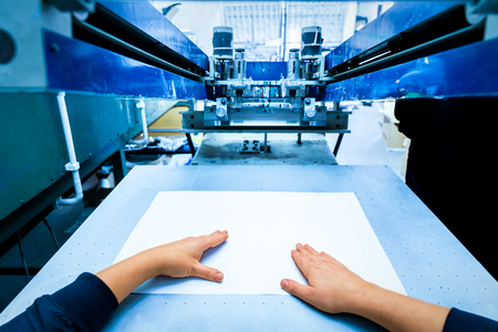 Worker preparing print screening metal machine. Industrial printer. Manufacture work. First person perspective.の写真素材