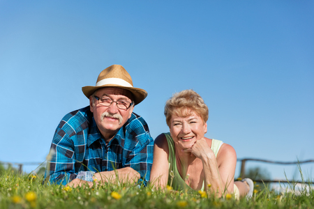 Senior couple lying on the summer field in green grass. Mature love and relationship.の写真素材