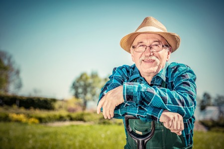 Portrait of a senior gardener standing in a garden with a shovel. Gardeningの写真素材