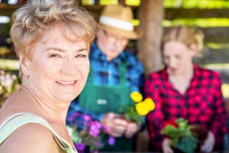 Grandmother looking into the camera. Mature woman portrait in a garden. Planting flowers with the family.の写真素材