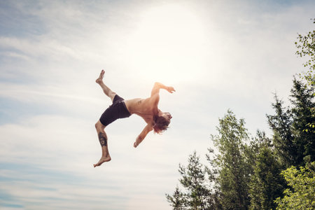 Young man doing a backflip in the air. Jumping and sport acitivity.