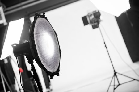 Photography studio with professional lighting equipment. Focus on a beauty dish with a grid.