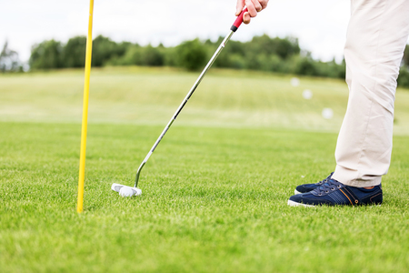 Golfer putting ball in the hole on a golf course close up.の写真素材
