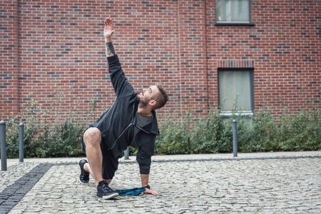 A young man is stretching his body on the streets of the city. Fit lifestyle.の写真素材