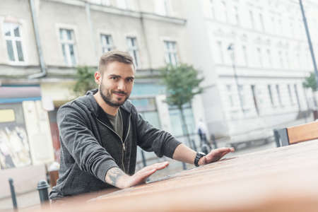 Young handsome bearded man, supporting his hand on a counter, looking at the camera. Millenial man.の写真素材
