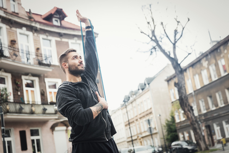 Sporty young man streching his arm. Sportsman daily routine in a city site.の写真素材