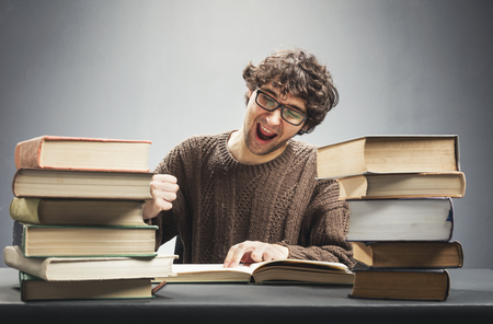 Young man reading a book, studying, looking joyful and excited. Geek concept.の写真素材