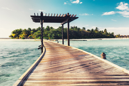 Wooden jetty with arch leading to a tropical island. Water landscape. Maldives destinationの写真素材