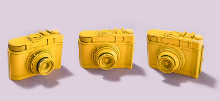 Three yellow cameras standing on pastel pink background. Photography concept.の写真素材