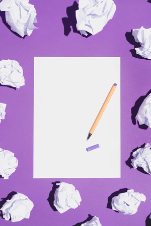 Blank white page and fineliner laying on vivid violet background, creased paper around it.の写真素材