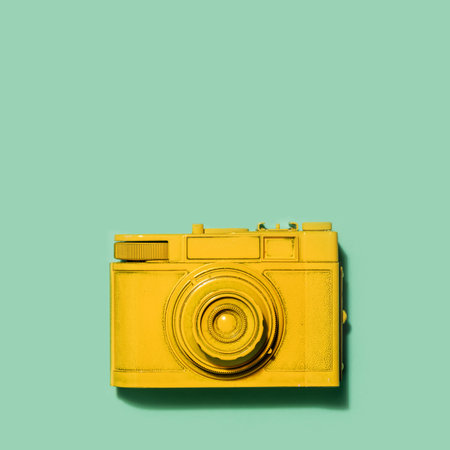 Old yellow camera laying on a pastel green background. Photography. Copyspace.