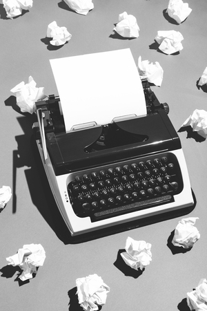 Oldschool typewriter and pieces of creased paper nearby. Black and white.の写真素材