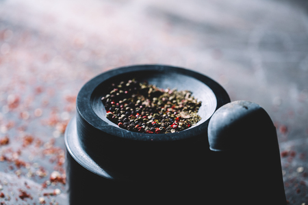 Half-crushed dried peppercorns placed in a mortar. Freshness of natural spices. Traditional ways of preparing food.の写真素材