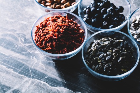 Bowls with different superfoods on a dark marble kitchen counter. Clean eating. Healthy diet.の写真素材