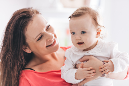 Happy mother holding her baby daughter, looking at her. Motherhood concept.の写真素材