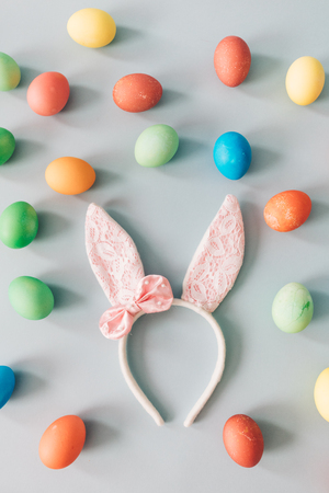 Furry headband with pink bunny ears laying on the floor, surrounded by colorful dyed eggs. Easter.の写真素材