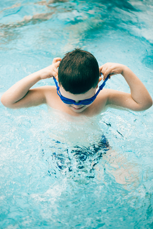 Little boy in a swimming pool with his diving goggles on. Water park. Summer activities.の写真素材