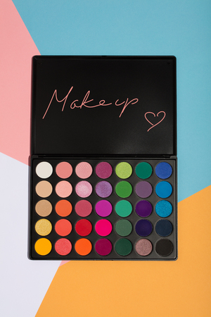 Makeup palette on a colorful geometrical background. MAKEUP writing and a heart.の写真素材