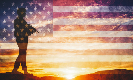 Armed soldier with rifle standing and looking on horizon. USA flag. Silhouette at sunset. War, army, military, guard.の写真素材