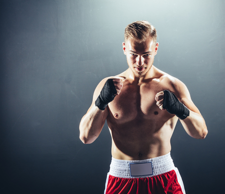 Boxer standing in fighting position on dark background. Professional fighter. Boxing.の写真素材