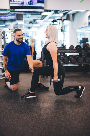 Woman exercising with personal trainer at the gym. Workout assistance. Healthy lifestyle.