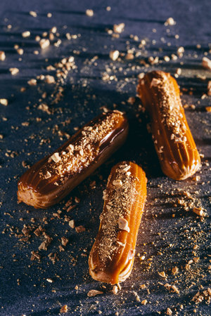 Three caramel cakes with gold sprinkles on dark background. Traditional French pastry. Top view.