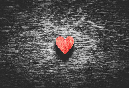 Red wooden heart on black wooden background. Love symbol. Valentine's Day.