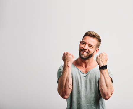 Happy successful handsome man celebrating and looking to the sideの写真素材