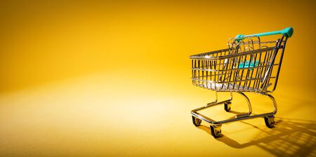 Shopping cart on yellow background in spotlight. Conceptual image with copy-space.の写真素材