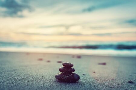 Stones pyramid on the beach at sunset. Zen, harmony, peace concept. Vintage toneの写真素材