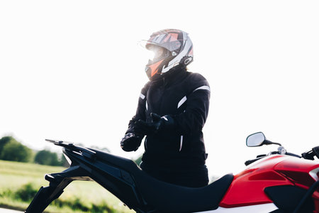Woman preparing to drive a motorbike. Wearing gloves on a roadside