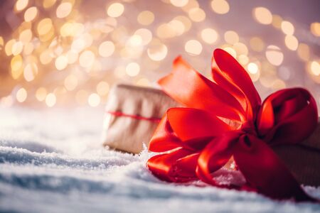 Christmas gift on snow, wrapped in eco paper. Lights shiningの写真素材
