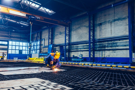 Worker cutting metal, steel with acetylene torch in big factory. Heavy industry, shipyard