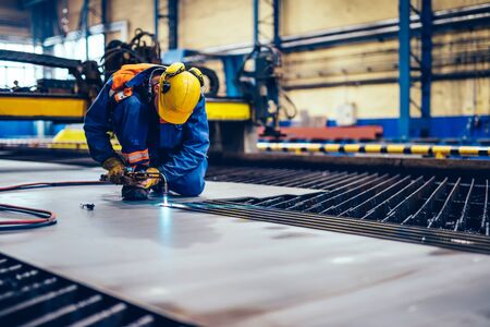 Worker cutting metal, steel with acetylene torch in big factory. Heavy industry, shipyardの写真素材