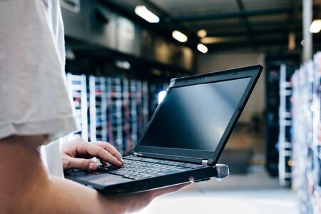 IT specialist working on computer in bitcoin and crypto currency mining farm. Big data center. High tech server computers at workの写真素材