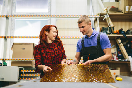 Man and woman working on glass pane in glazier workshop. Industry and manufactory production