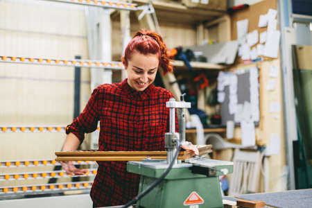 Woman worker sticking together a wooden frame with glue. Industry, manual workの写真素材