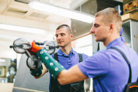 Glazier worker holding a big mirror glass pane in workshop. Industry and manufactory productionの写真素材
