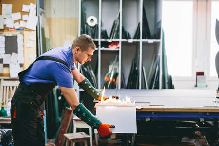 Glazier worker cutting glass with fire in a workshop. Industryの写真素材