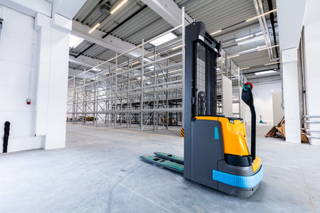 Pallet jack in new warehouse industrial hall with racking storage racks. Shelving system