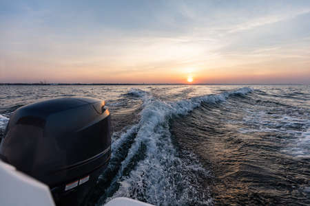 Fast motorboat ride on sea at sunset. Wake pattern behindの写真素材
