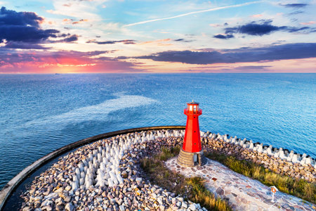 Red lighthouse on rocky harbor at sunsetGdansk, Poland