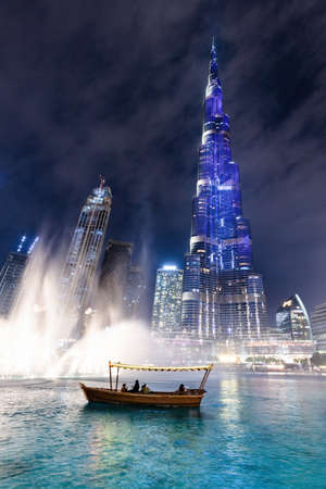 Traditional boat and Burj Khalifa illumination with fountain show in Dubai UAE downtown at night.のeditorial素材