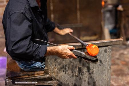 Glass blower at work in workshop in Murano, Italy, making handmade glasswareの写真素材