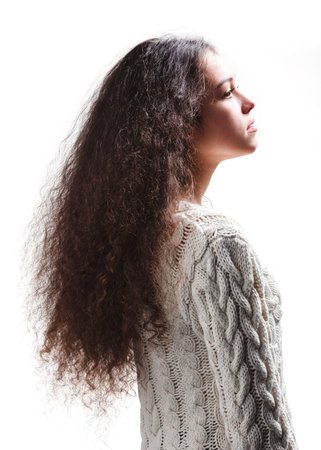 Teenager girl with long curly hair face side view on whiteの写真素材