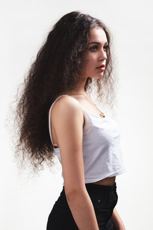 Teenager girl with long curly hair portrait posing in studioの写真素材