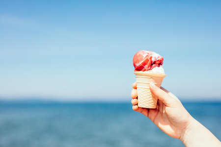 Ice cream in woman's hand by the sea. Summertimeの写真素材
