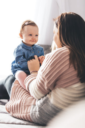 Mother and her baby daughter having fun on couch at home. happy family