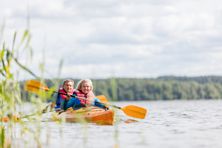 Happy senior active couple kayaking on lake enjoying time togetherの写真素材