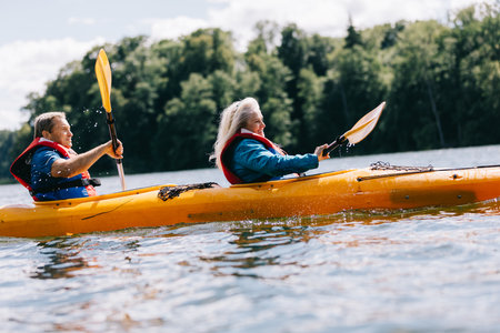 Happy senior active couple kayaking on lake enjoying time togetherの写真素材